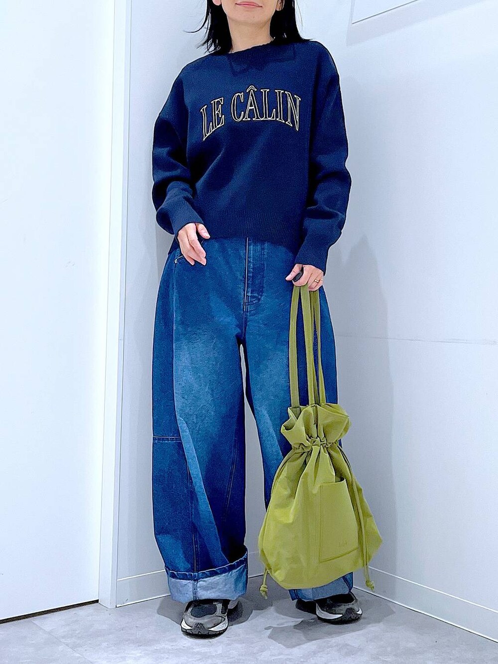 グリーン系のトートバッグ、ブルー系のニット/セーター、ブルー系のデニムパンツを着用したレディースの冬コーディネートの6枚目の写真