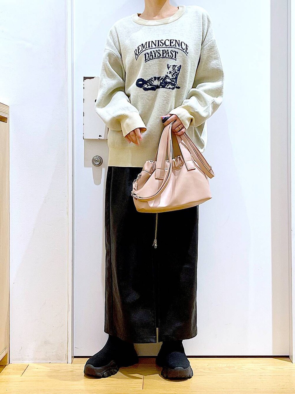 ブラック系のスカート、ブラック系のブーツ、ピンク系のショルダーバッグを着用したレディースの冬コーディネートの6枚目の写真