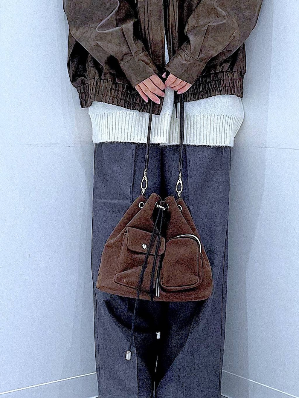 ブラウン系のブルゾン、ブラウン系のショルダーバッグ、ブラック系のブーツを着用したレディースの冬コーディネートの9枚目の写真