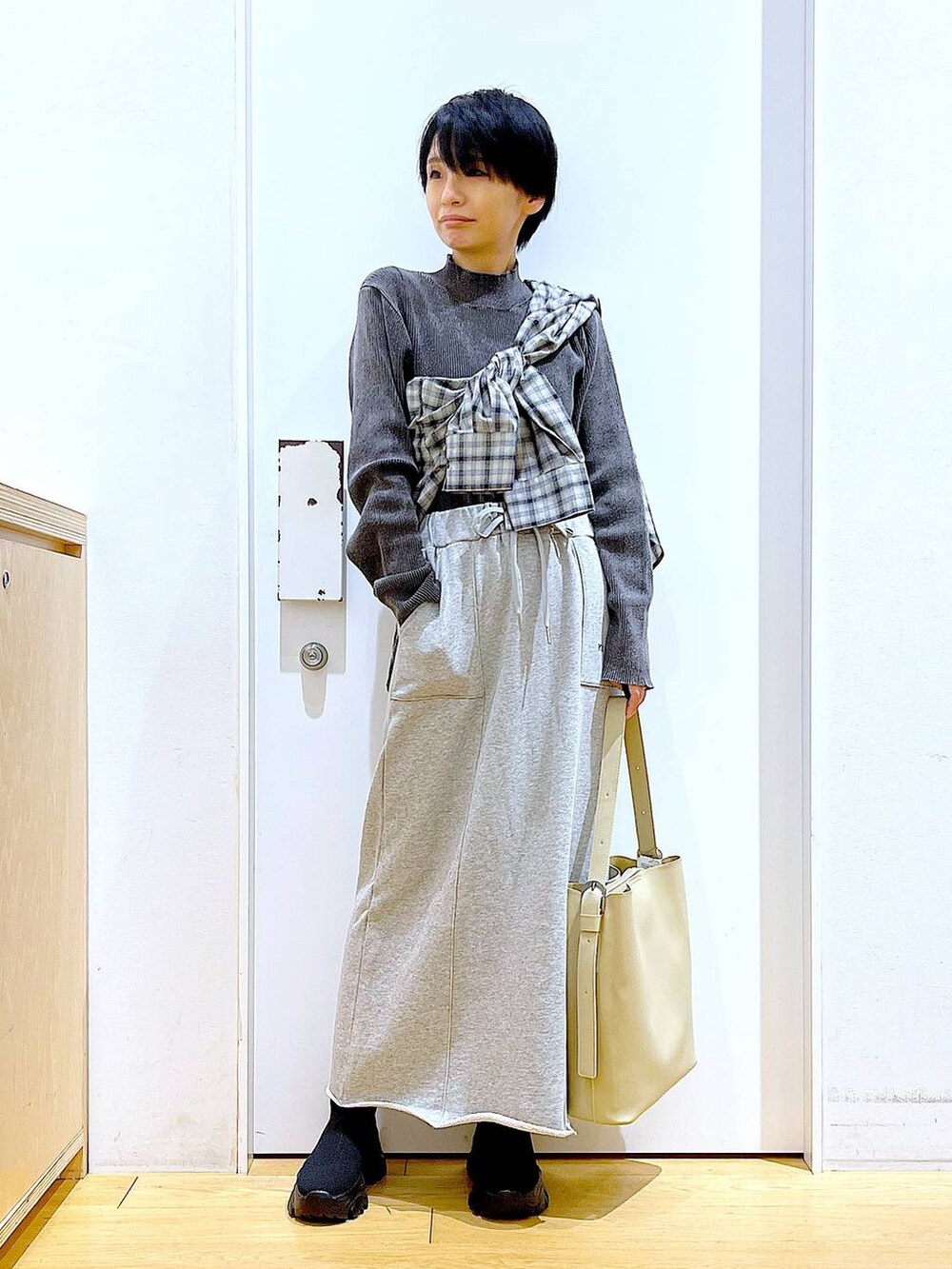 ブラック系のブーツ、ホワイト系のショルダーバッグ、ベージュ系のシャツ/ブラウスを着用したレディースの春コーディネートの2枚目の写真