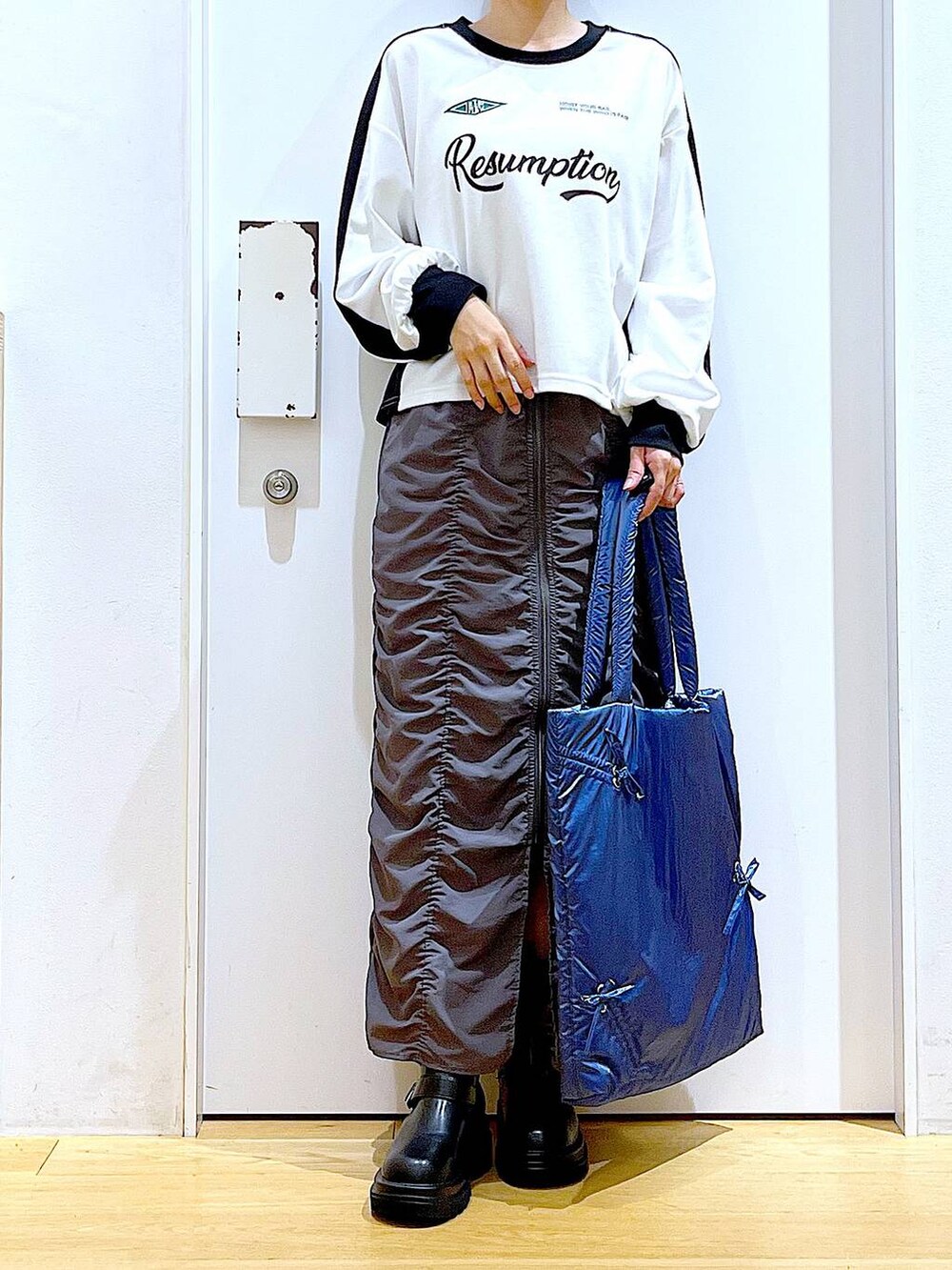 ブラック系のブーツ、ブルー系のトートバッグ、ホワイト系のTシャツ/カットソーを着用したレディースの秋コーディネートの6枚目の写真