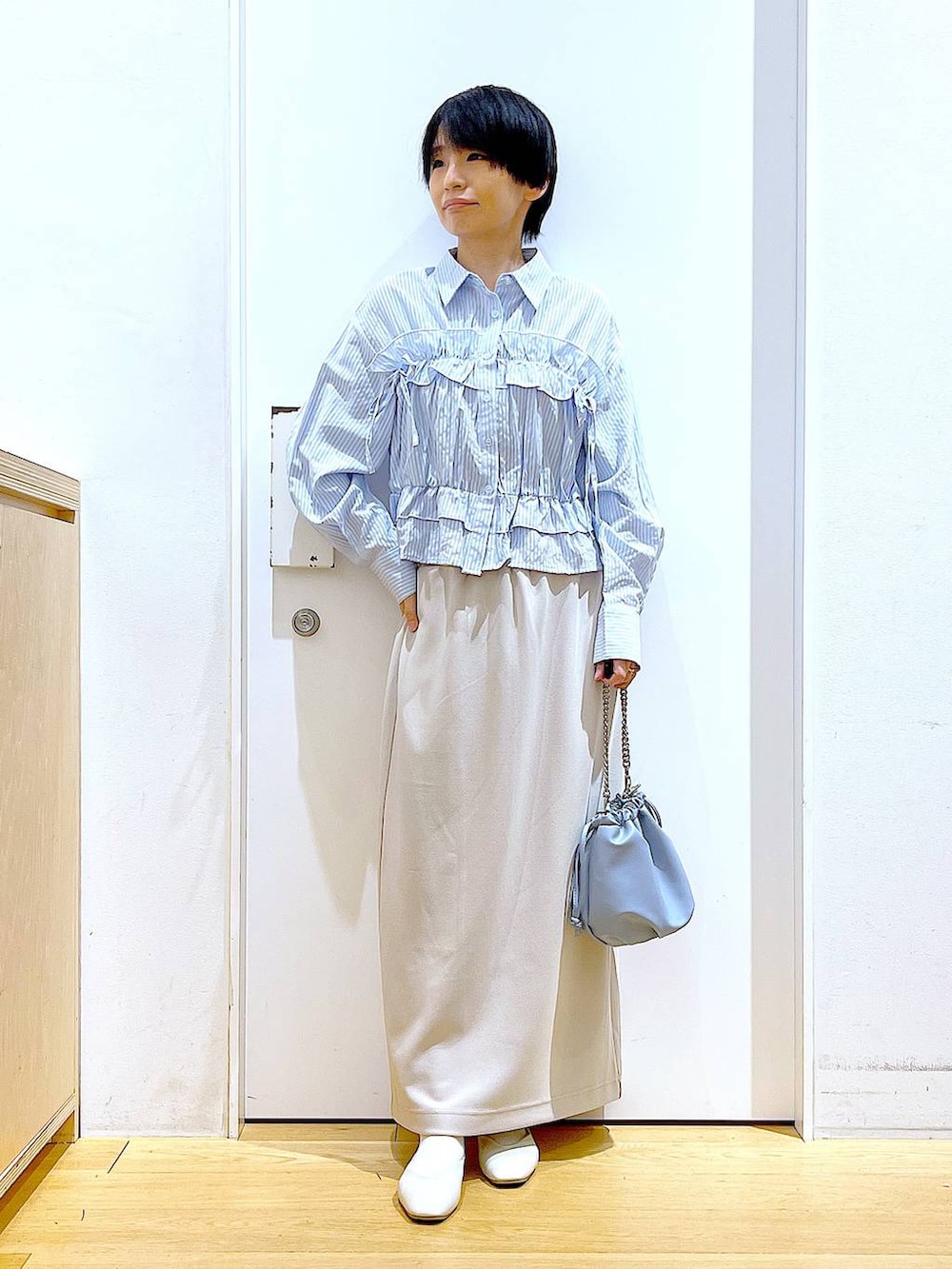 ブルー系のショルダーバッグ、ホワイト系のパンプス、ベージュ系のスカートを着用したレディースの春コーディネートの2枚目の写真