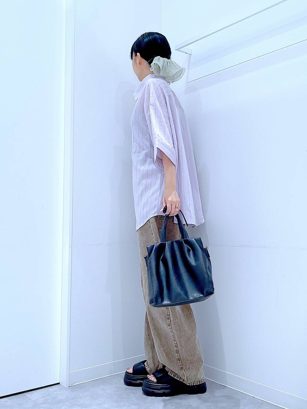 ブラウン系のデニムパンツ、ブラック系のサンダル、ブラック系のハンドバッグを着用したレディースの夏コーディネートの3枚目の写真