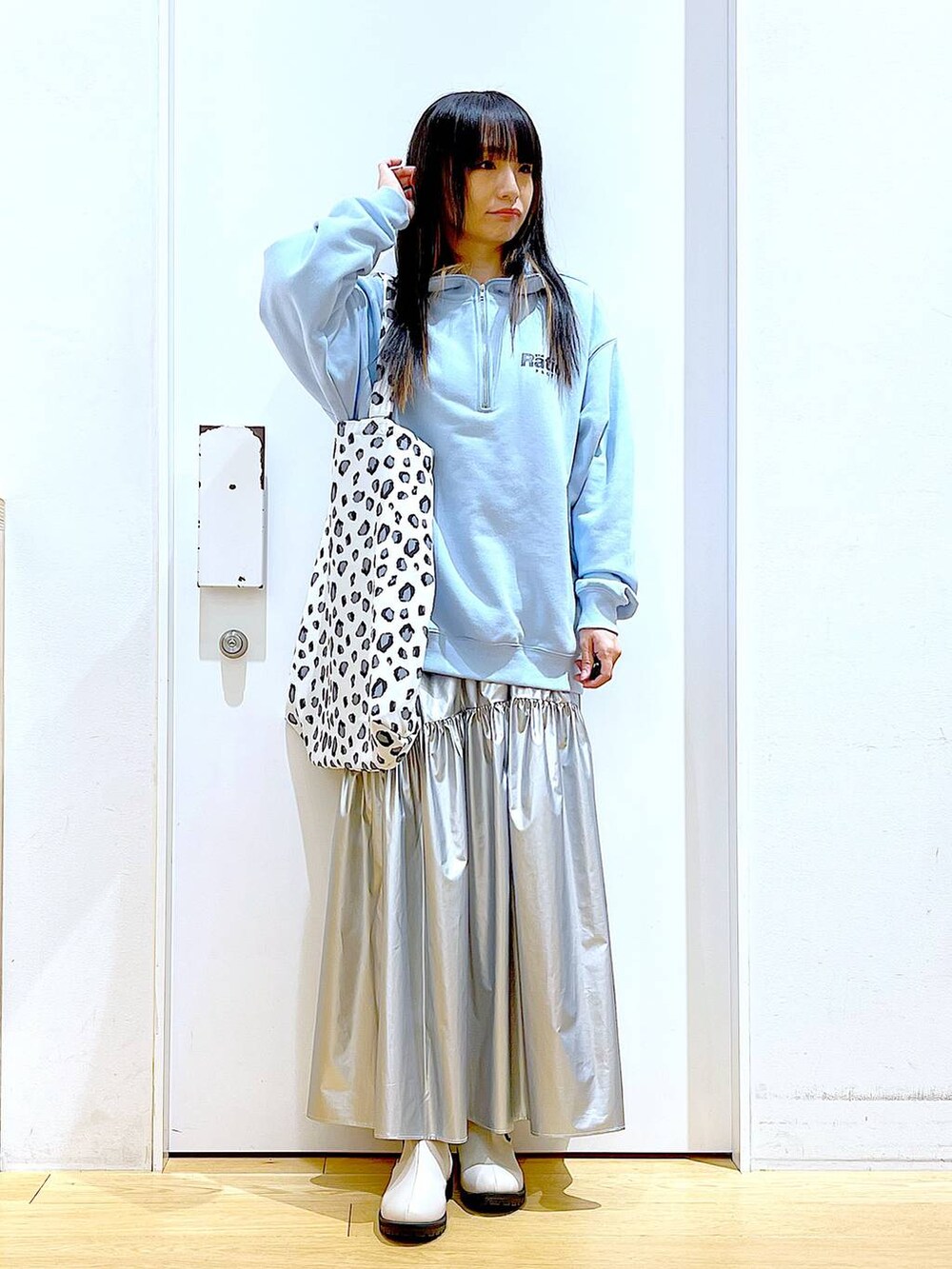 ブルー系のスウェット、シルバー系のスカート、ベージュ系のブーツを着用したレディースの春コーディネートの2枚目の写真