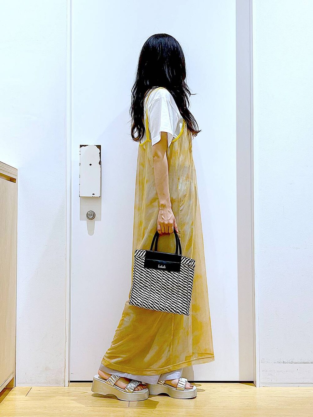 シルバー系のサンダル、オレンジ系のワンピース、ブラック系のショルダーバッグを着用したレディースの夏コーディネートの4枚目の写真