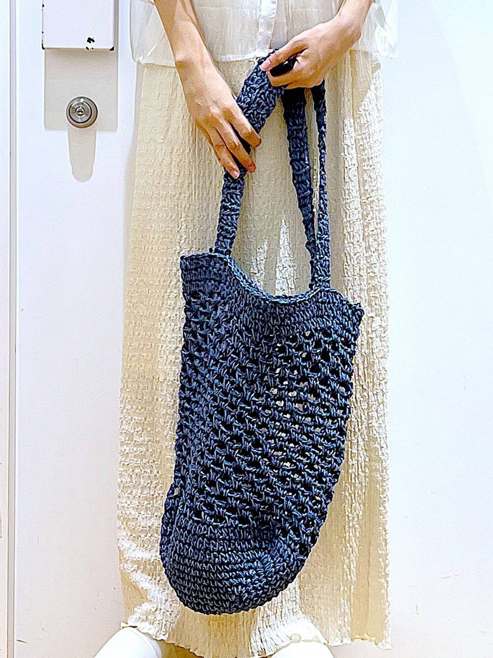 ホワイト系のサンダル、ブラック系のニット/セーター、ブルー系のトートバッグを着用したレディースの夏コーディネートの9枚目の写真