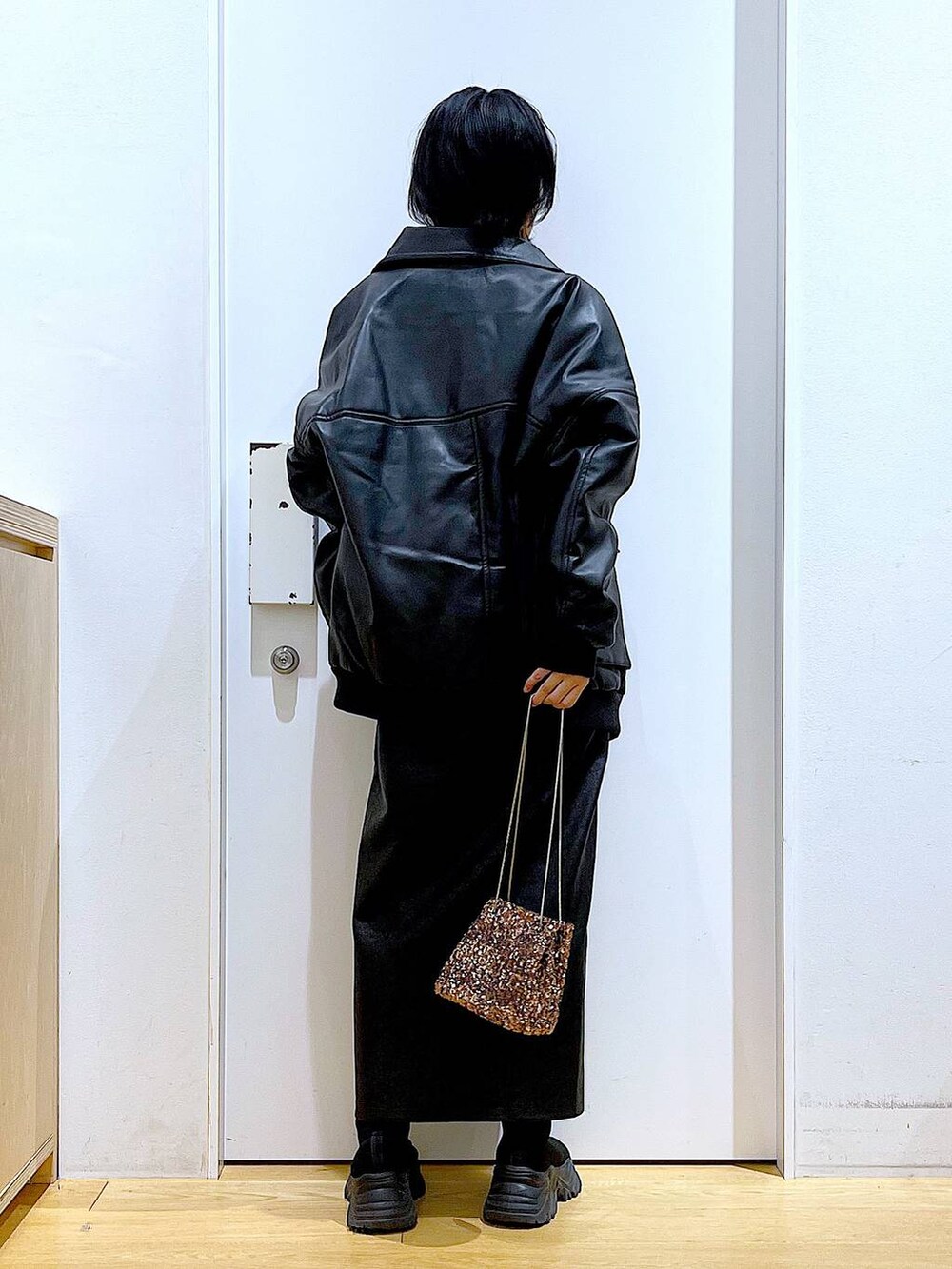 オレンジ系のニット/セーター、ブラウン系のスカート、ブラック系のブーツを着用したレディースの冬コーディネートの5枚目の写真