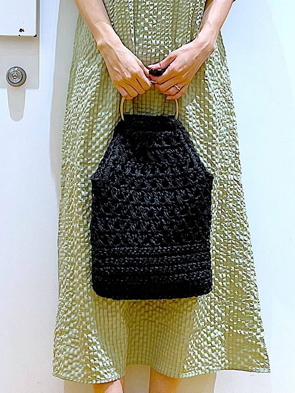 グリーン系のワンピース、ホワイト系のパンプス、ブラック系のハンドバッグを着用したレディースの春コーディネートの9枚目の写真