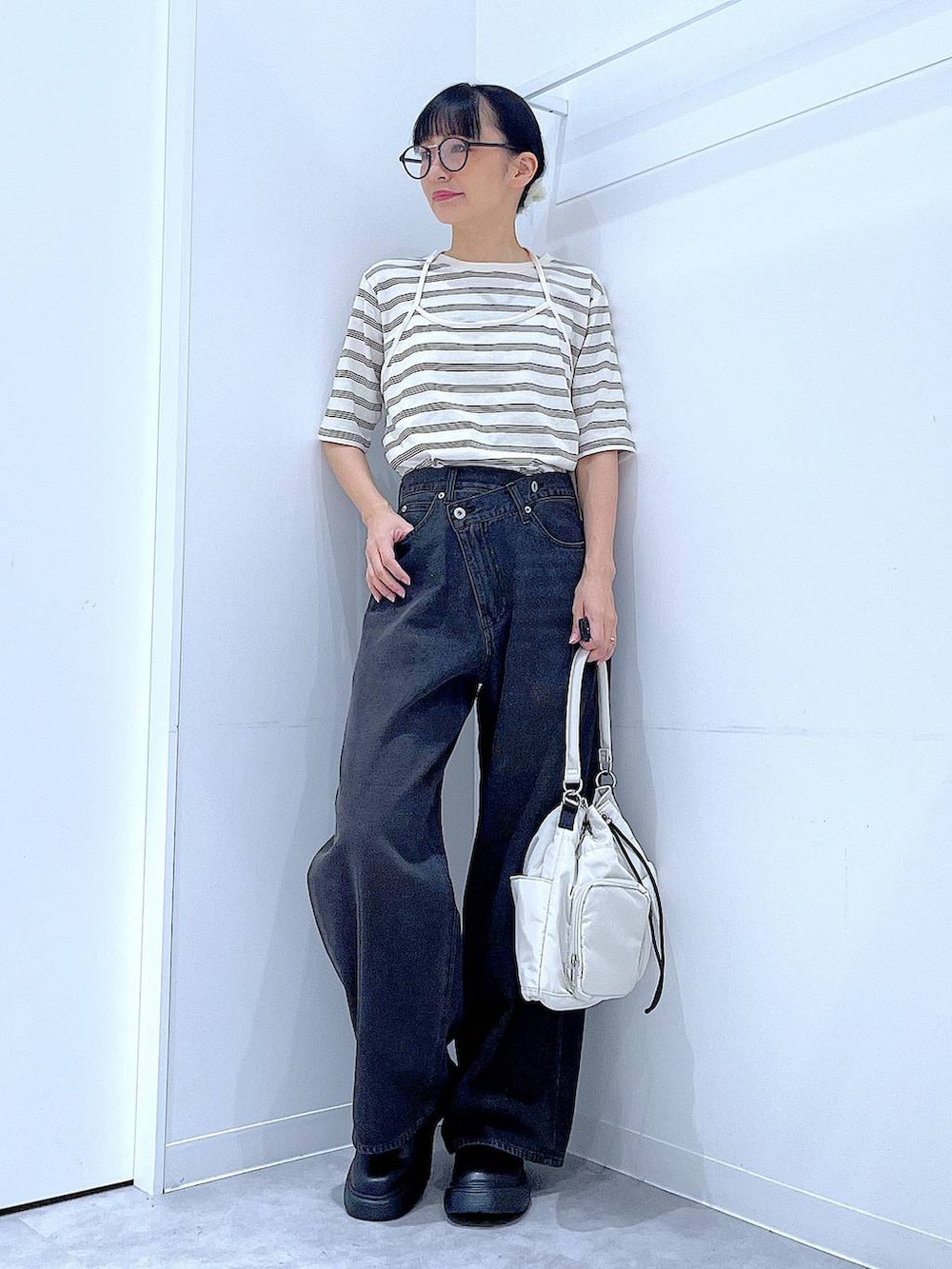 ブラック系のデニムパンツ、ホワイト系のハンドバッグ、ベージュ系のTシャツ/カットソーを着用したレディースの秋コーディネートの2枚目の写真