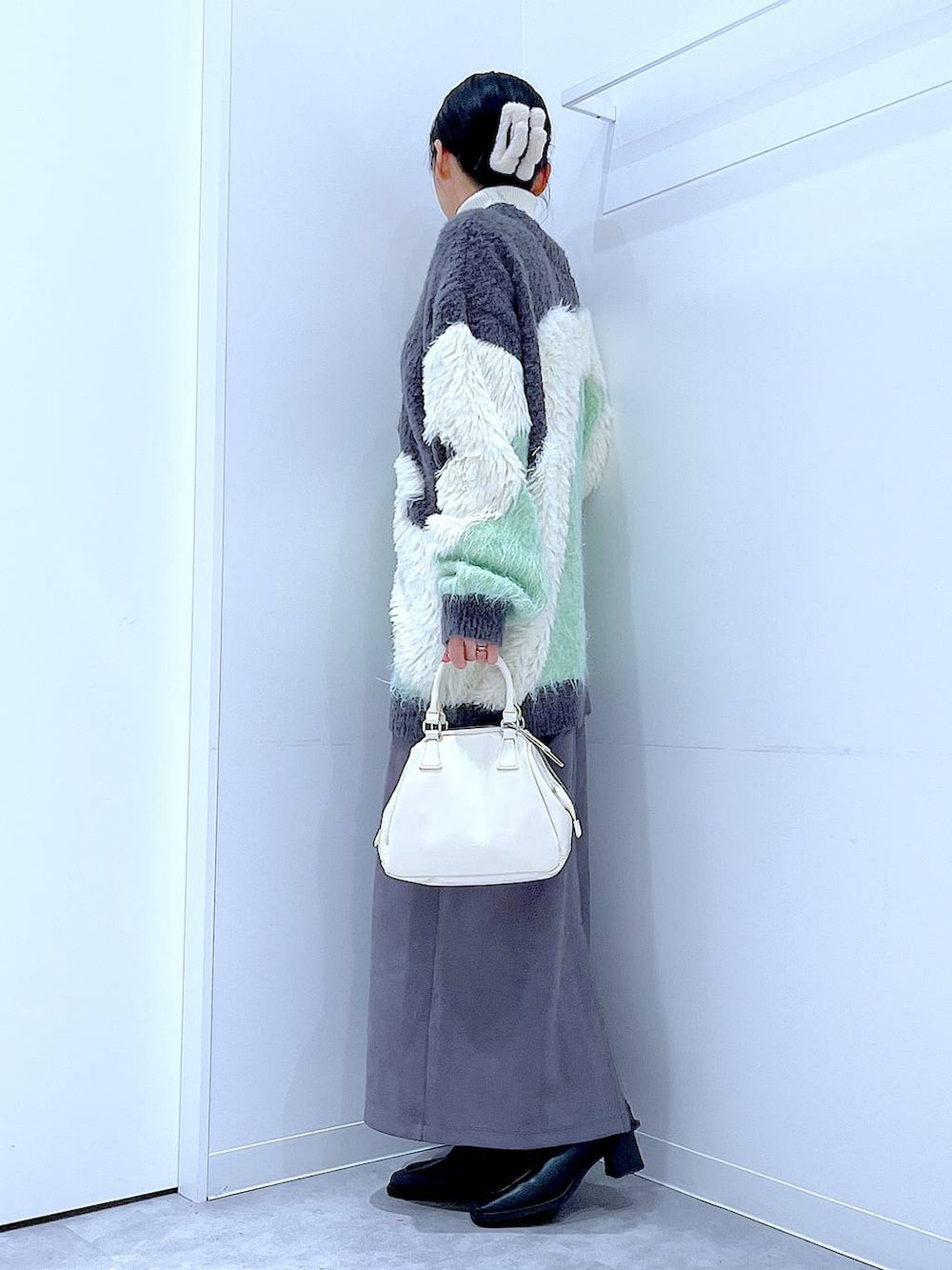 グリーン系のカーディガン/ボレロ、ブラック系のブーツ、ホワイト系のショルダーバッグを着用したレディースの冬コーディネートの3枚目の写真