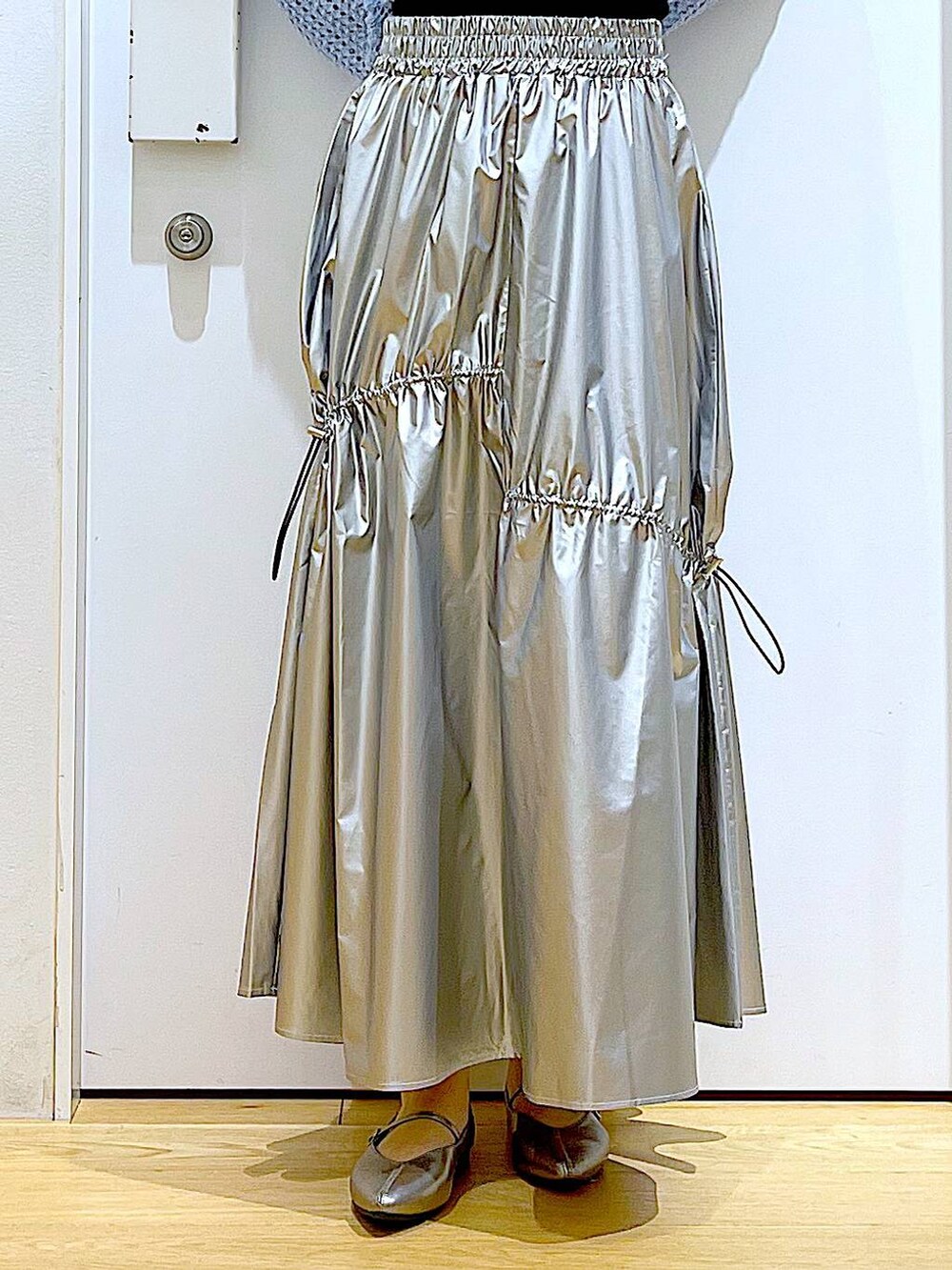 ブルー系のニット/セーター、シルバー系のスカート、ホワイト系のショルダーバッグを着用したレディースの春コーディネートの8枚目の写真