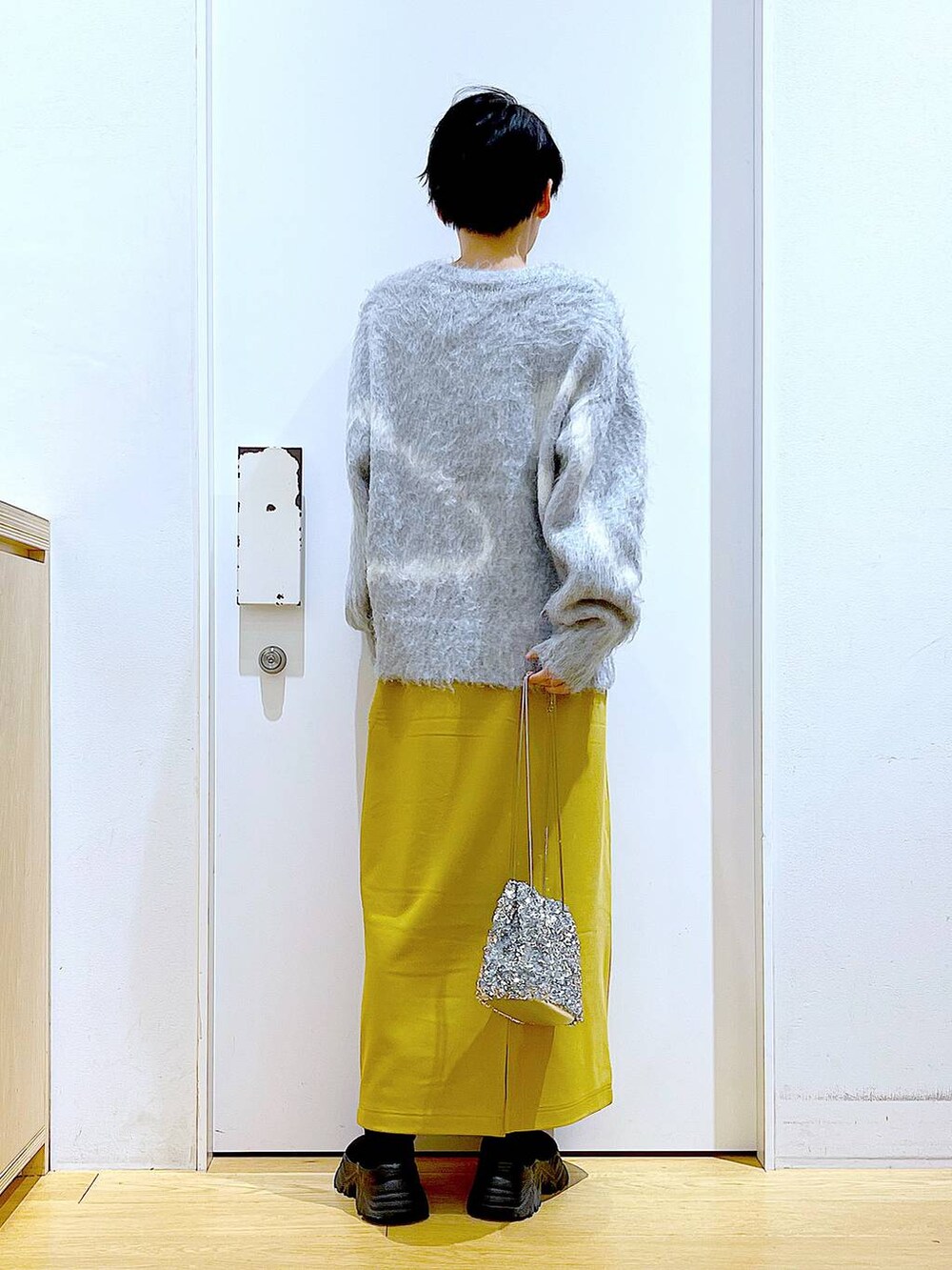 グレー系のニット/セーター、ブラック系のブーツ、イエロー系のスカートを着用したレディースの冬コーディネートの5枚目の写真