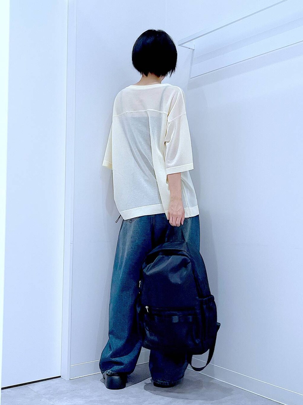 ブルー系のデニムパンツ、ブラック系のバックパック/リュック、ブラック系のサンダルを着用したレディースの夏コーディネートの5枚目の写真