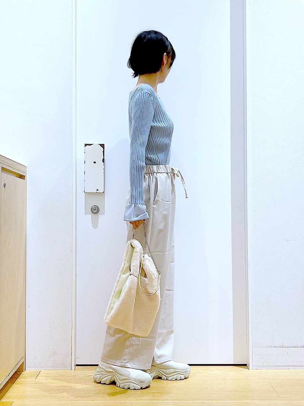 ブルー系のニット/セーター、ホワイト系のショルダーバッグ、ベージュ系のブーツを着用したレディースの冬コーディネートの4枚目の写真