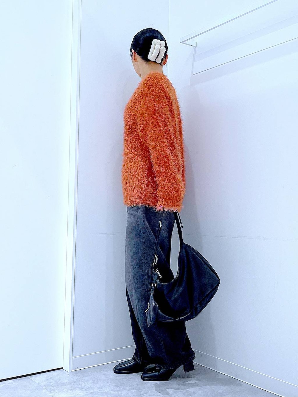 ブラック系のデニムパンツ、ブラック系のブーツ、ブラック系のショルダーバッグを着用したレディースの秋コーディネートの3枚目の写真