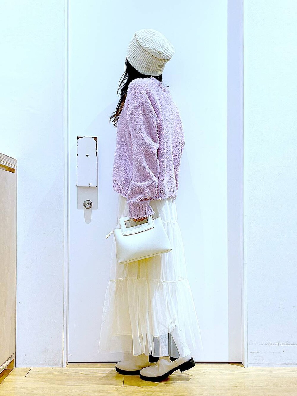 パープル系のニット/セーター、ベージュ系のブーツ、ホワイト系のショルダーバッグを着用したレディースの春コーディネートの3枚目の写真