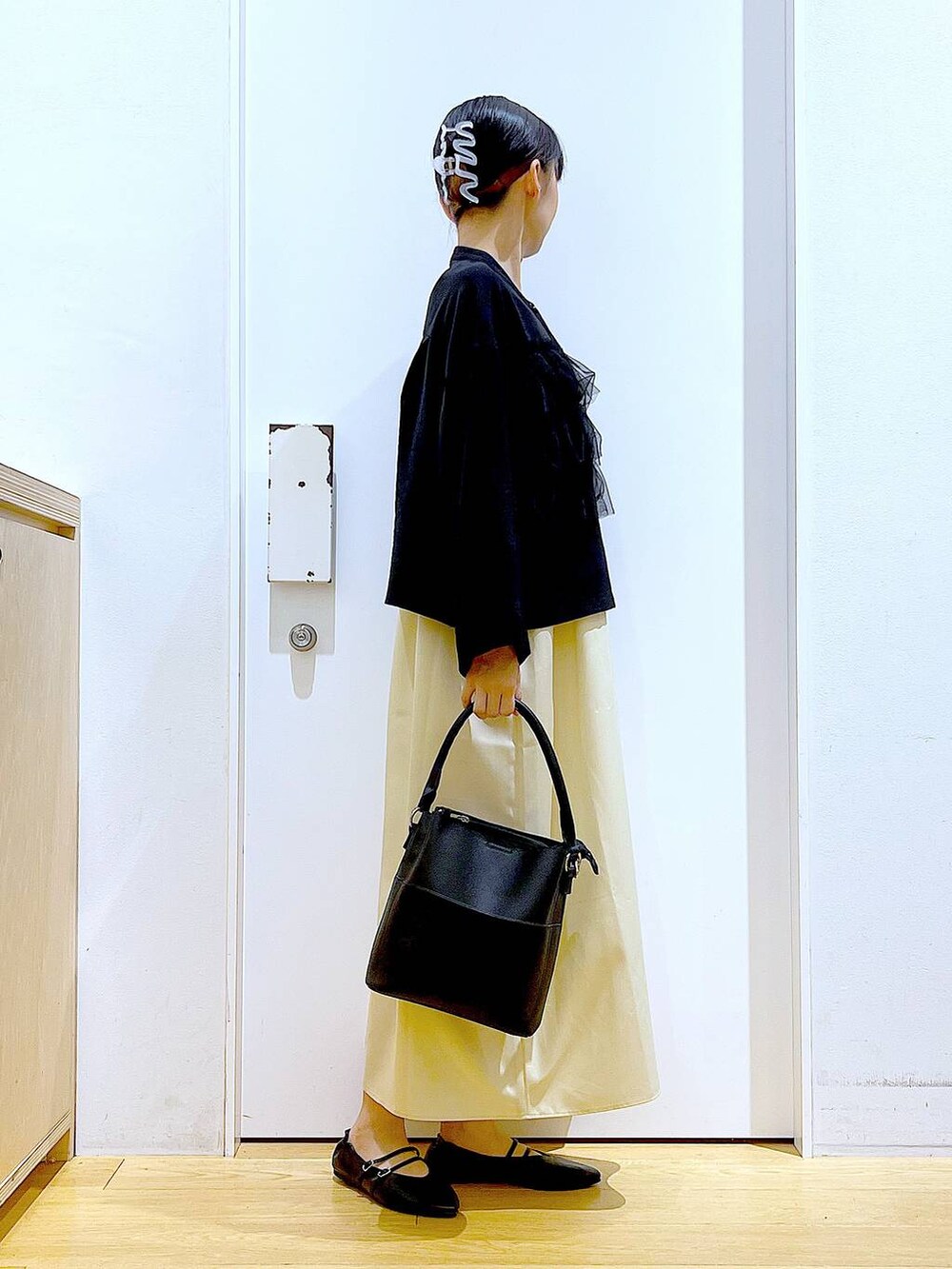 イエロー系のワンピース、ブラック系のショルダーバッグ、ブラック系のパンプスを着用したレディースの秋コーディネートの4枚目の写真