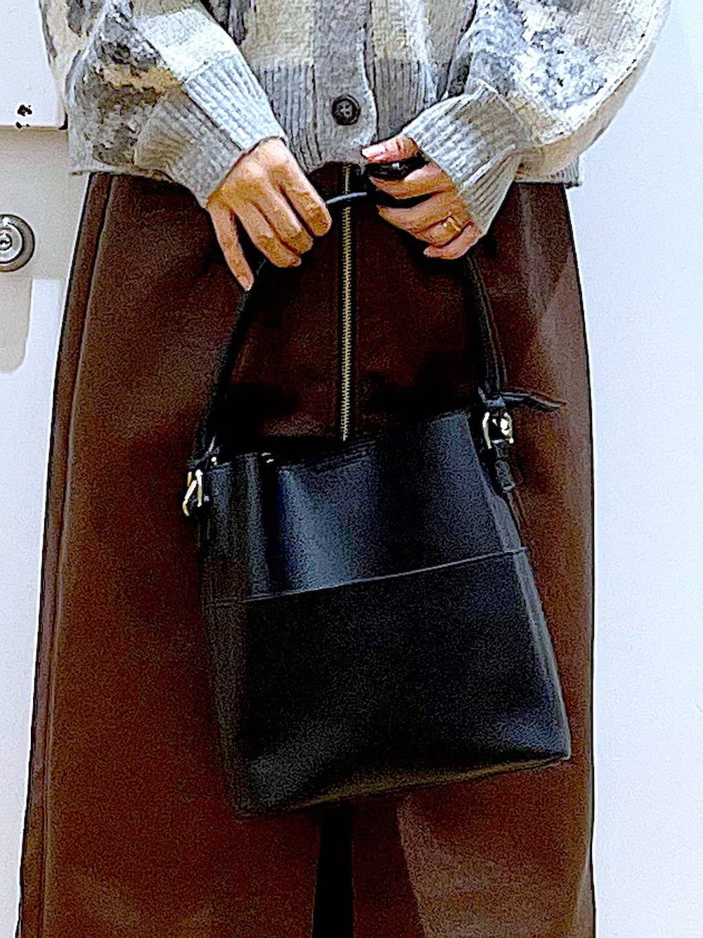 ブラウン系のスカート、ブラック系のショルダーバッグ、ブラック系のブーツを着用したレディースの冬コーディネートの9枚目の写真