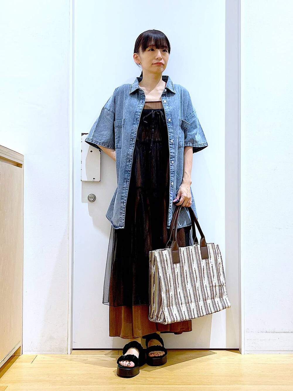 ブラック系のサンダル、ブラウン系のトートバッグ、ブラック系のワンピースを着用したレディースの夏コーディネートの2枚目の写真