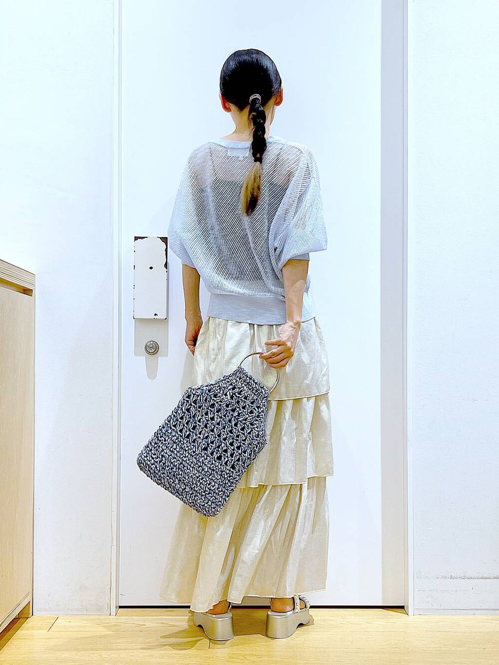 シルバー系のサンダル、ブルー系のハンドバッグ、ゴールド系のスカートを着用したレディースの夏コーディネートの5枚目の写真