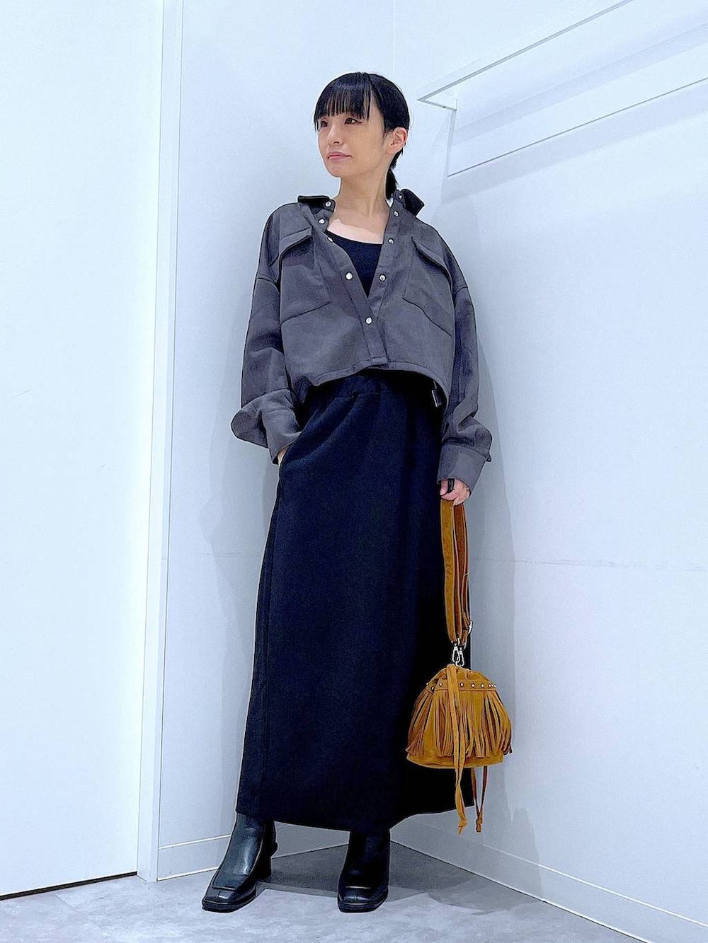 ブラック系のスカート、ブラック系のブーツ、グレー系のシャツ/ブラウスを着用したレディースの秋コーディネートの2枚目の写真