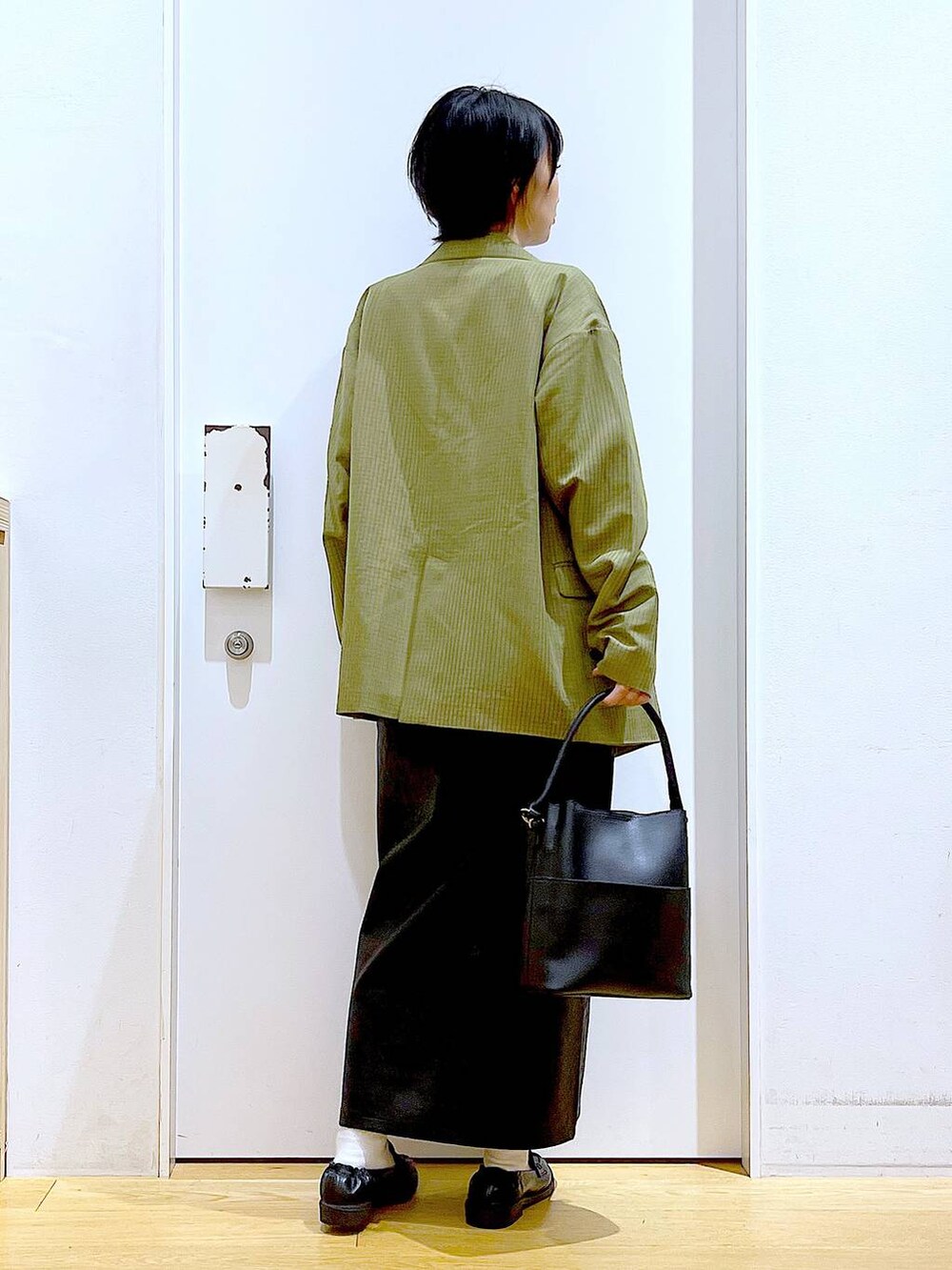 ホワイト系のベスト、ブラック系のスカート、ブラック系のショルダーバッグを着用したレディースの秋コーディネートの5枚目の写真