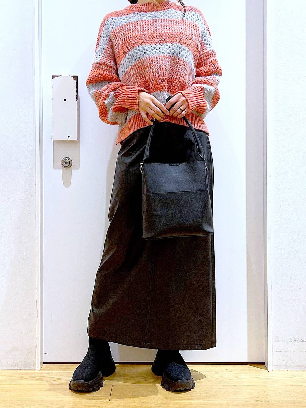 ブラック系のショルダーバッグ、ブラック系のブーツ、ブラック系のスカートを着用したレディースの冬コーディネートの6枚目の写真