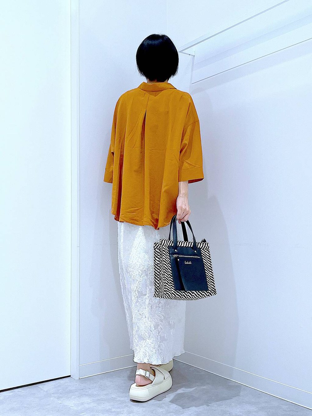 ブラック系のショルダーバッグ、ホワイト系のサンダル、ホワイト系のスカートを着用したレディースの夏コーディネートの5枚目の写真