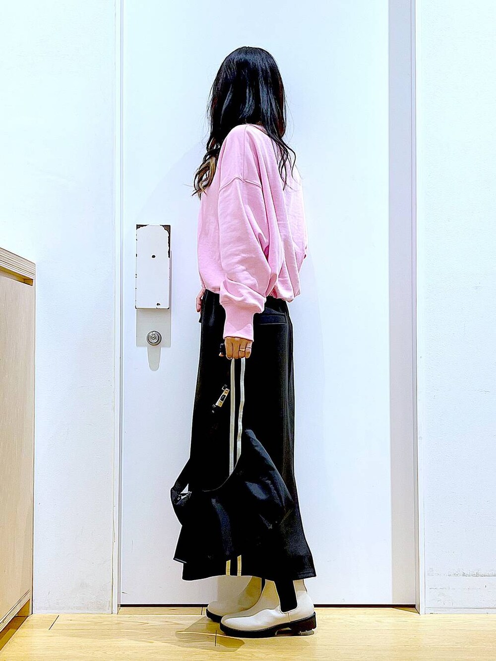 ピンク系のスウェット、ベージュ系のブーツ、ブラック系のショルダーバッグを着用したレディースの春コーディネートの3枚目の写真