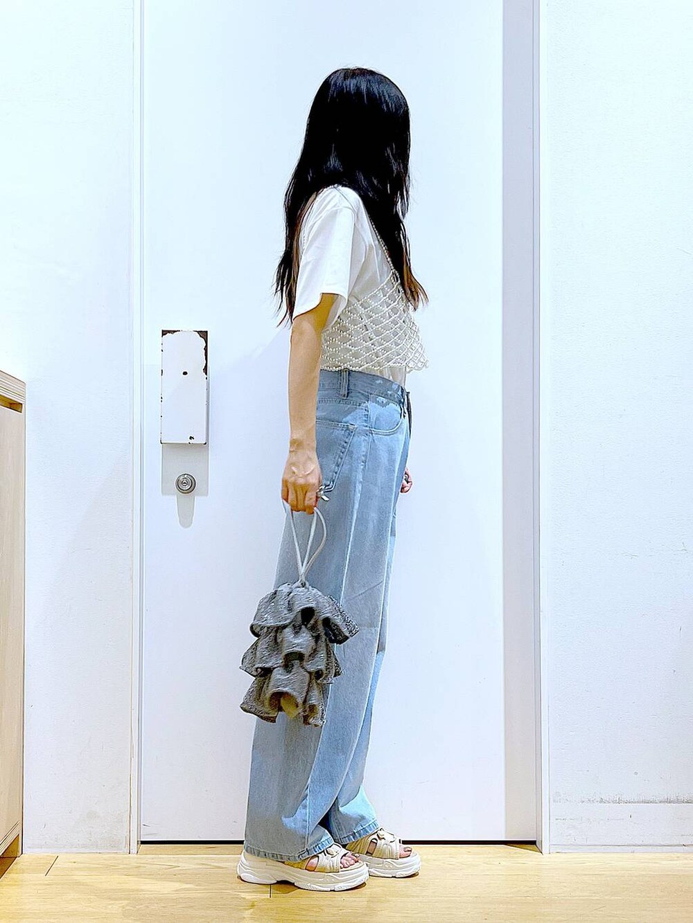 シルバー系のショルダーバッグ、ベージュ系のサンダル、ブルー系のデニムパンツを着用したレディースの夏コーディネートの4枚目の写真