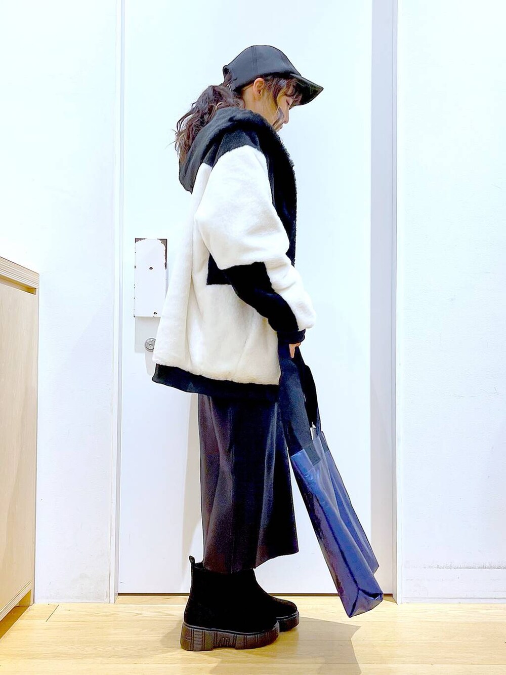 グレー系のスカート、ホワイト系のブルゾン、ブラック系のブーツを着用したレディースの冬コーディネートの4枚目の写真