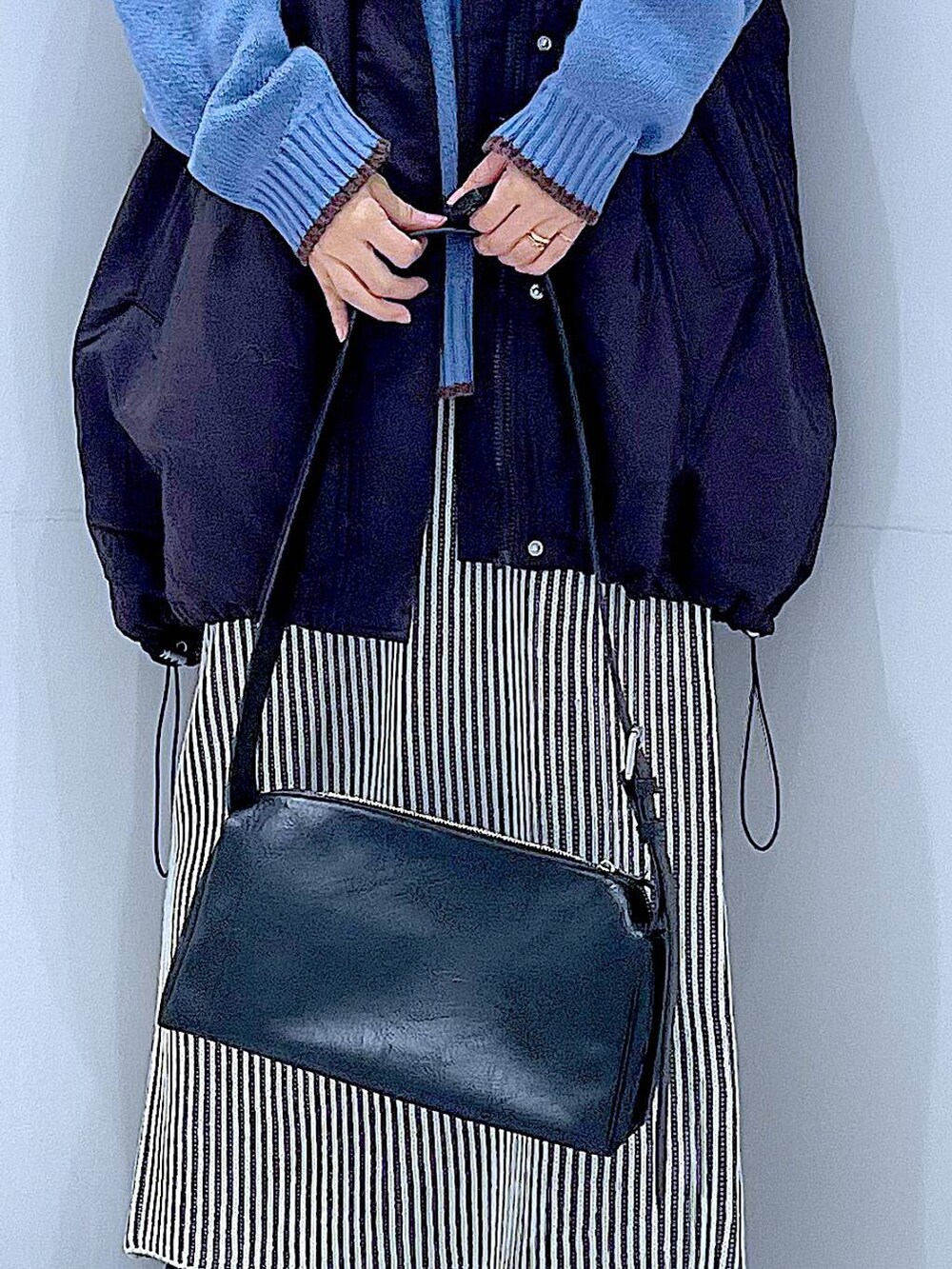 ブラック系のブルゾン、ベージュ系のスカート、ブラック系のブーツを着用したレディースの冬コーディネートの9枚目の写真