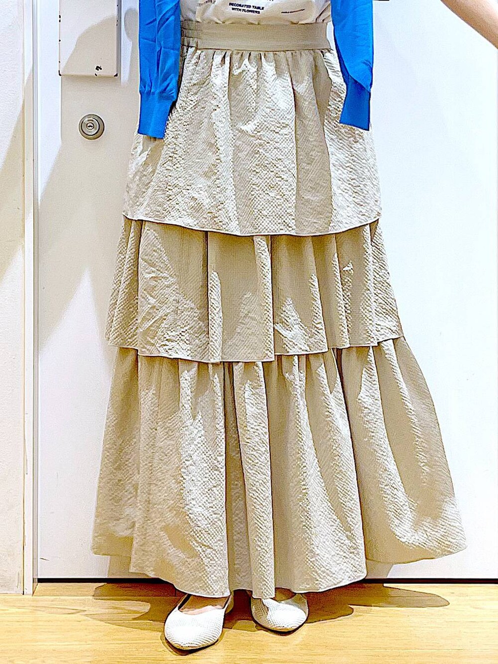シルバー系のショルダーバッグ、ブルー系のカーディガン/ボレロ、ホワイト系のパンプスを着用したレディースの春コーディネートの8枚目の写真