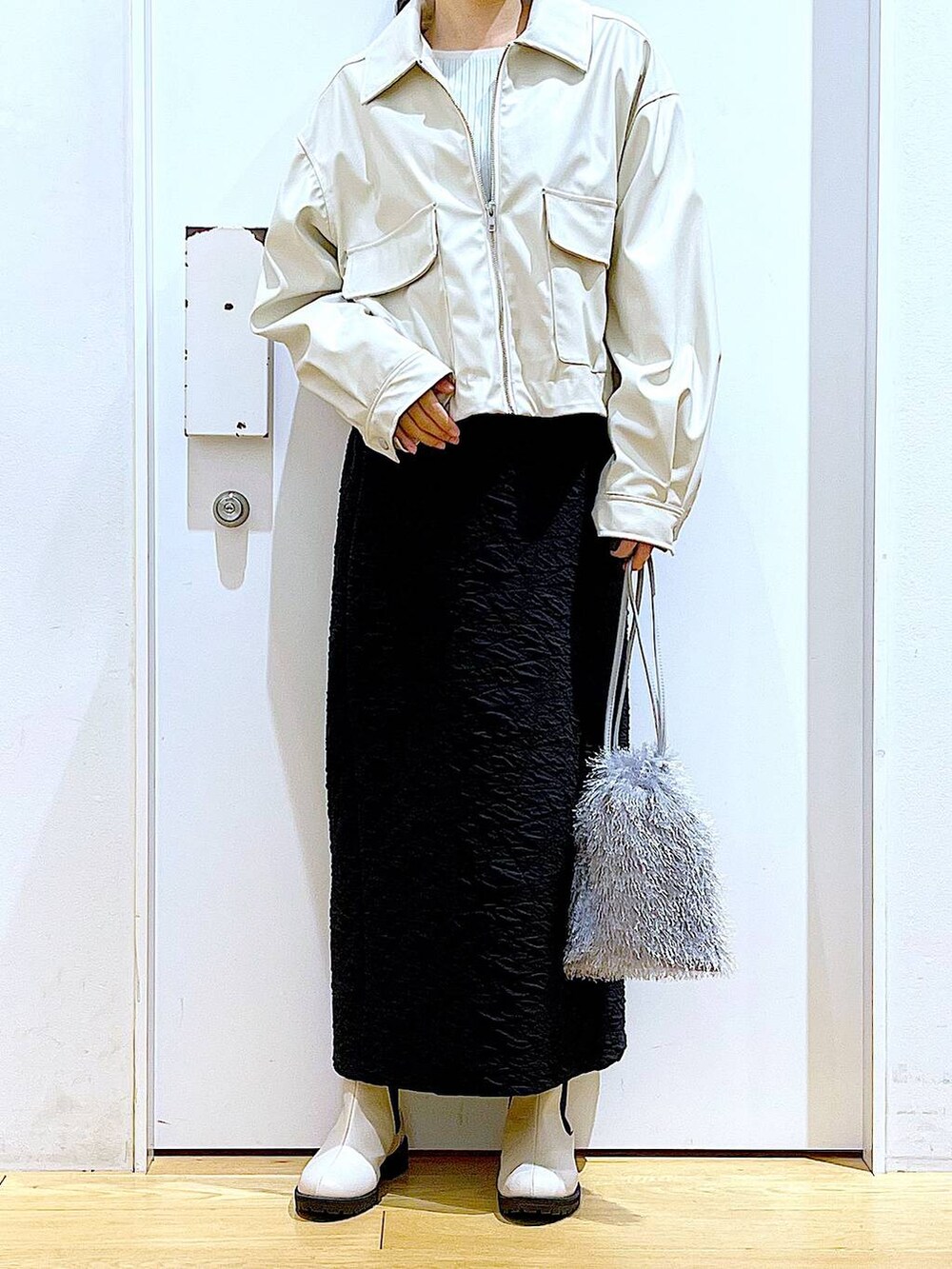 ブラック系のスカート、ベージュ系のブルゾン、ベージュ系のブーツを着用したレディースの春コーディネートの6枚目の写真