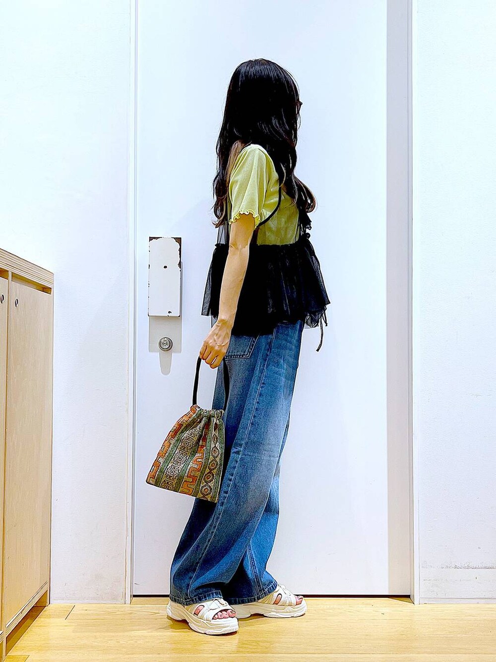 ブラウン系のショルダーバッグ、ホワイト系のサンダル、ブルー系のデニムパンツを着用したレディースの夏コーディネートの5枚目の写真