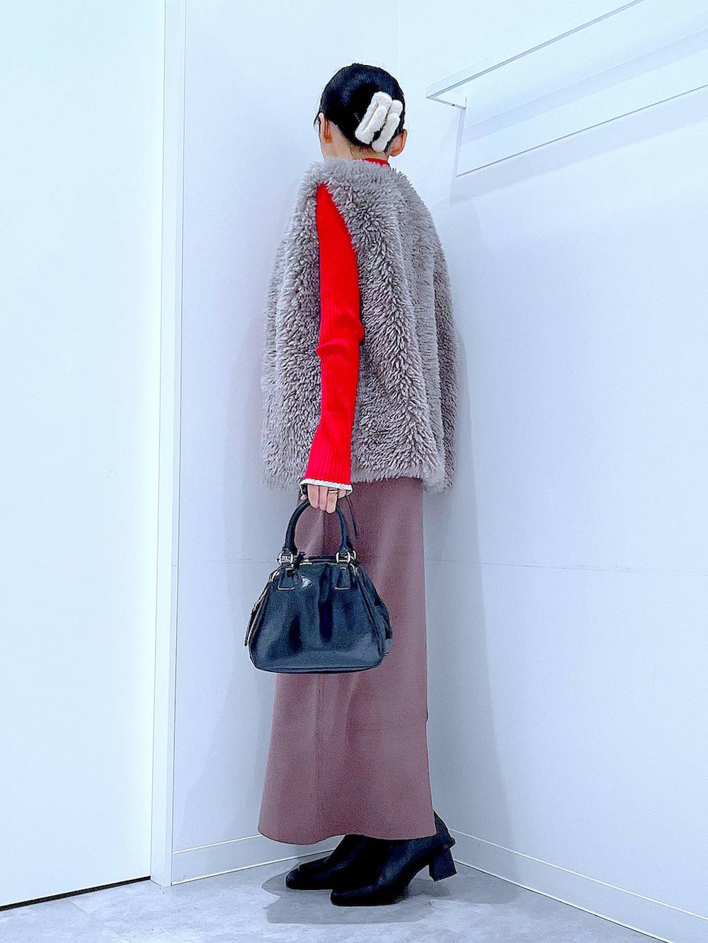 グレー系のベスト、レッド系のニット/セーター、ブラック系のブーツを着用したレディースの冬コーディネートの3枚目の写真