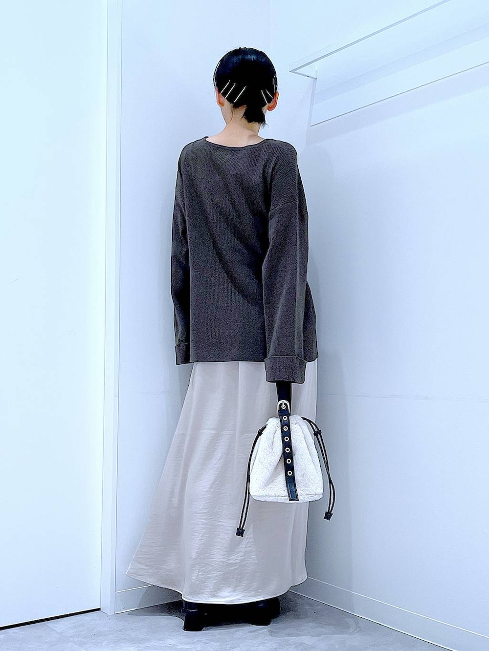 ホワイト系のハンドバッグ、ベージュ系のスカート、ブラック系のブーツを着用したレディースの秋コーディネートの5枚目の写真