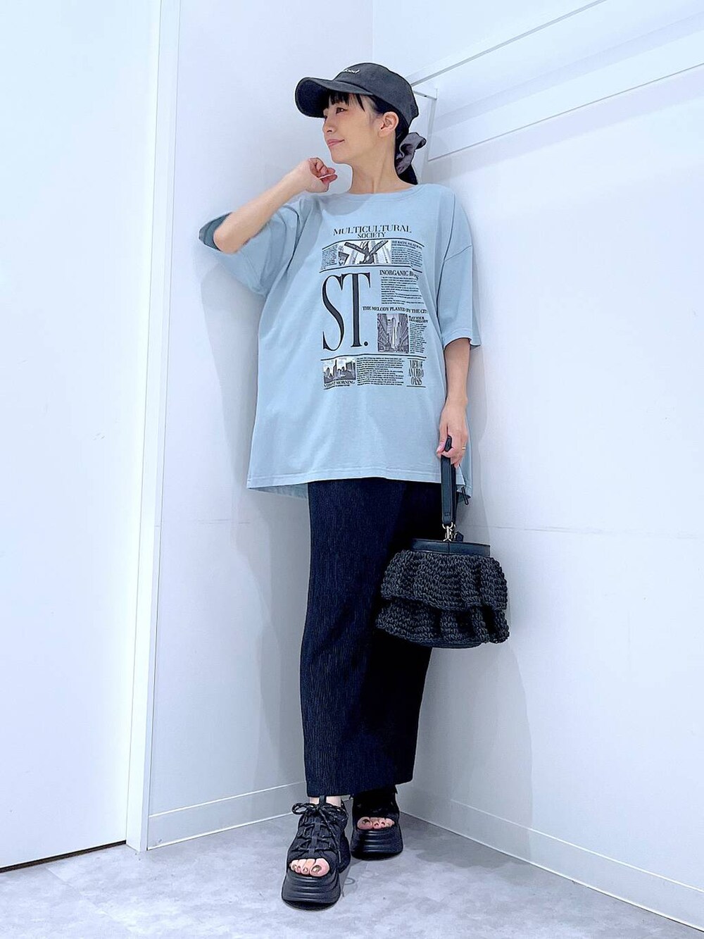 ブラック系のショルダーバッグ、ブラック系のサンダル、ブルー系のTシャツ/カットソーを着用したレディースの夏コーディネートの2枚目の写真
