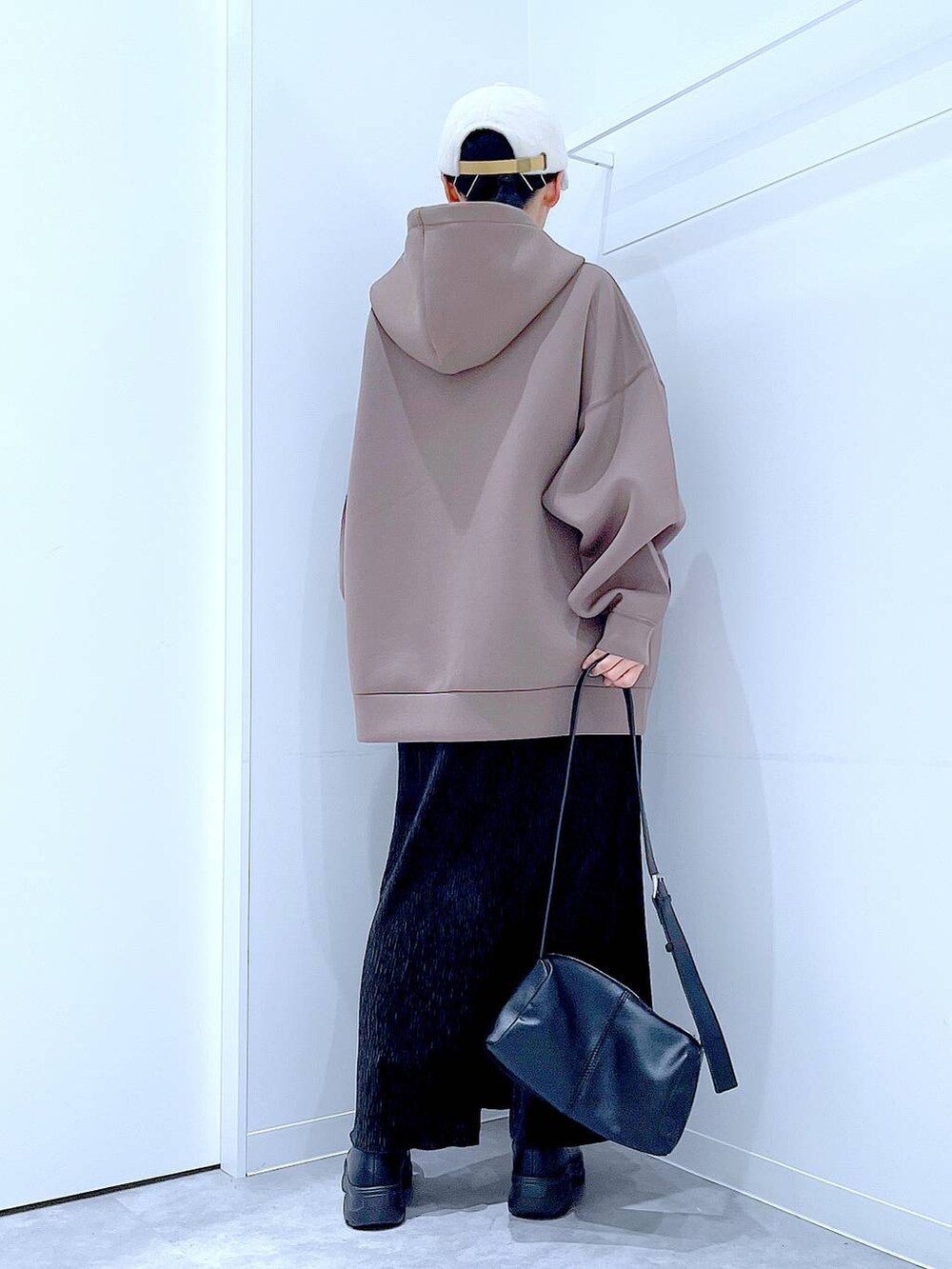 ブラック系のショルダーバッグ、ブラック系のブーツ、ブラウン系のパーカーを着用したレディースの秋コーディネートの5枚目の写真