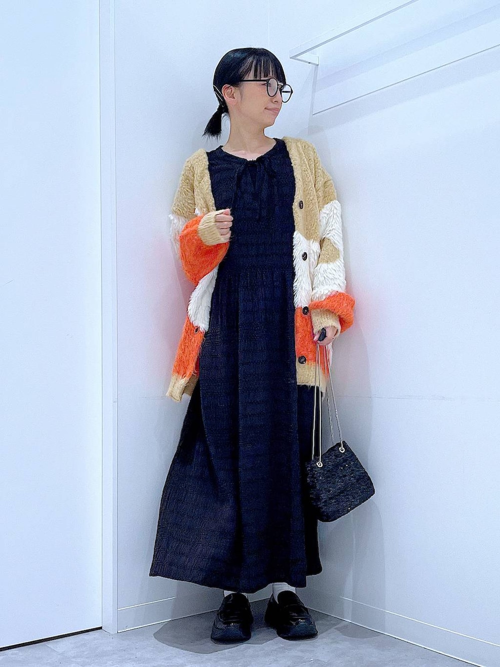 ブラック系のショルダーバッグ、ブラック系のローファー、オレンジ系のカーディガン/ボレロを着用したレディースの秋コーディネートの2枚目の写真