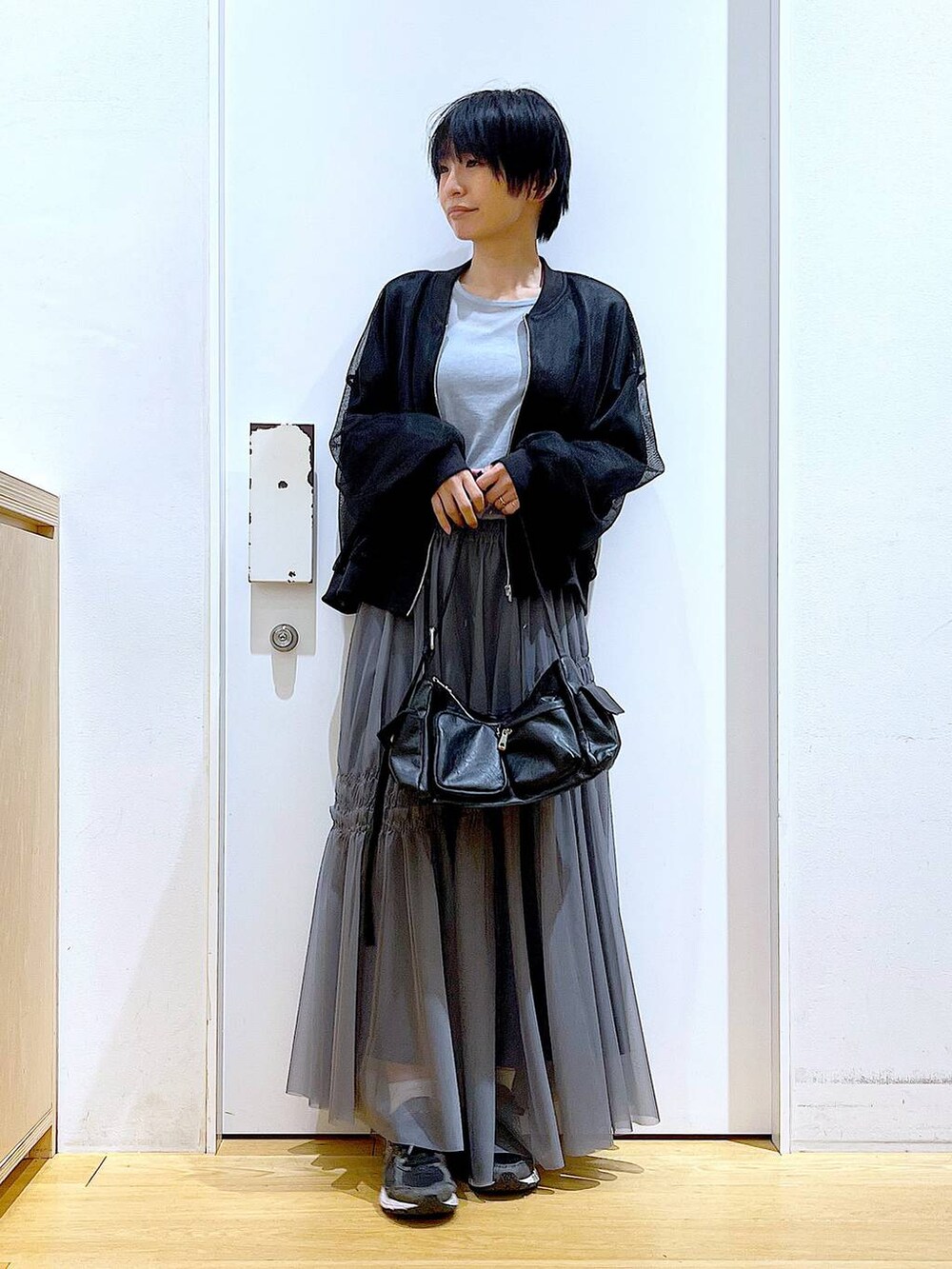 ブラック系のショルダーバッグ、ブラック系のブルゾン、ブルー系のTシャツ/カットソーを着用したレディースの春コーディネートの2枚目の写真