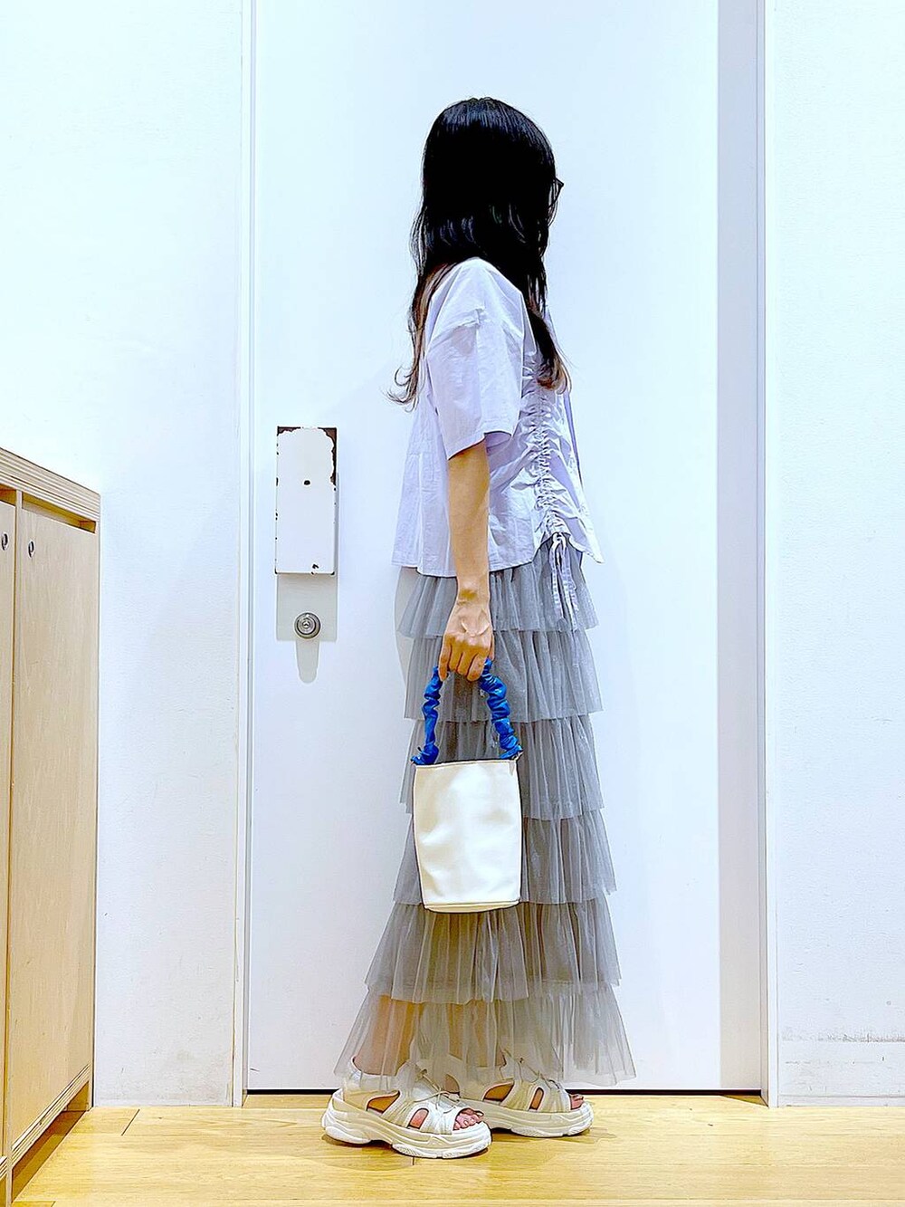 ブルー系のショルダーバッグ、ホワイト系のサンダル、グレー系のスカートを着用したレディースの夏コーディネートの4枚目の写真