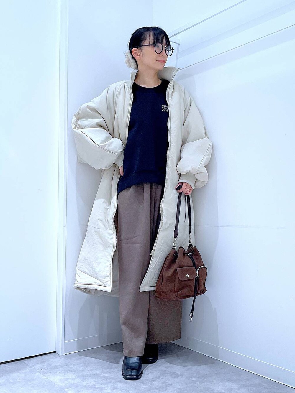 ホワイト系のブルゾン、ブラウン系のショルダーバッグ、ブラック系のブーツを着用したレディースの冬コーディネートの2枚目の写真
