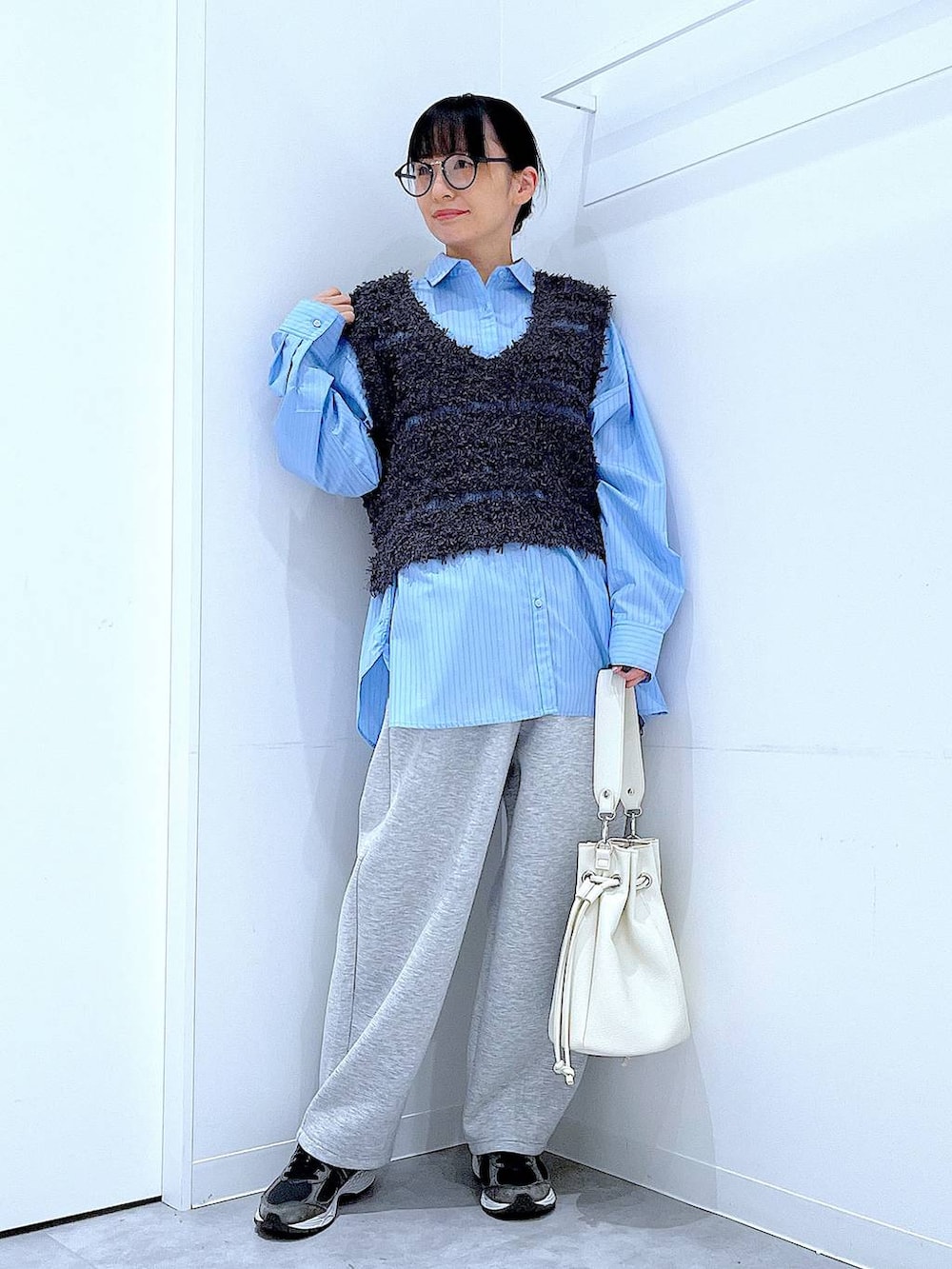 ブルー系のシャツ/ブラウス、ホワイト系のショルダーバッグ、グレー系のベストを着用したレディースの春コーディネートの2枚目の写真