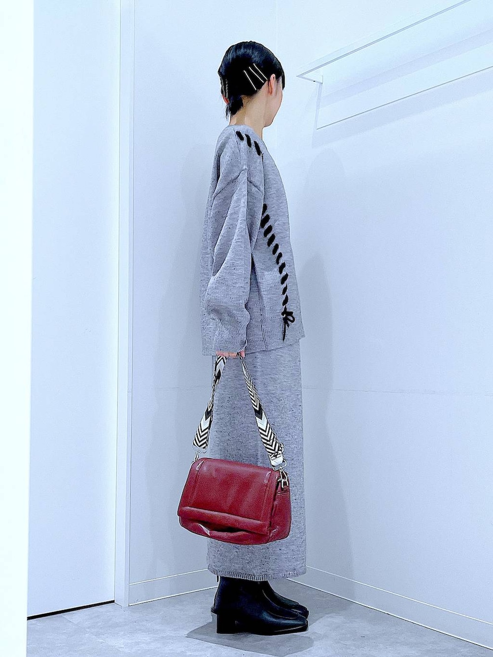 グレー系のニット/セーター、レッド系のショルダーバッグ、グレー系のスカートを着用したレディースの冬コーディネートの4枚目の写真