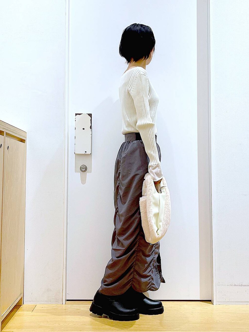 ホワイト系のニット/セーター、ホワイト系のショルダーバッグ、ブラック系のブーツを着用したレディースの秋コーディネートの4枚目の写真