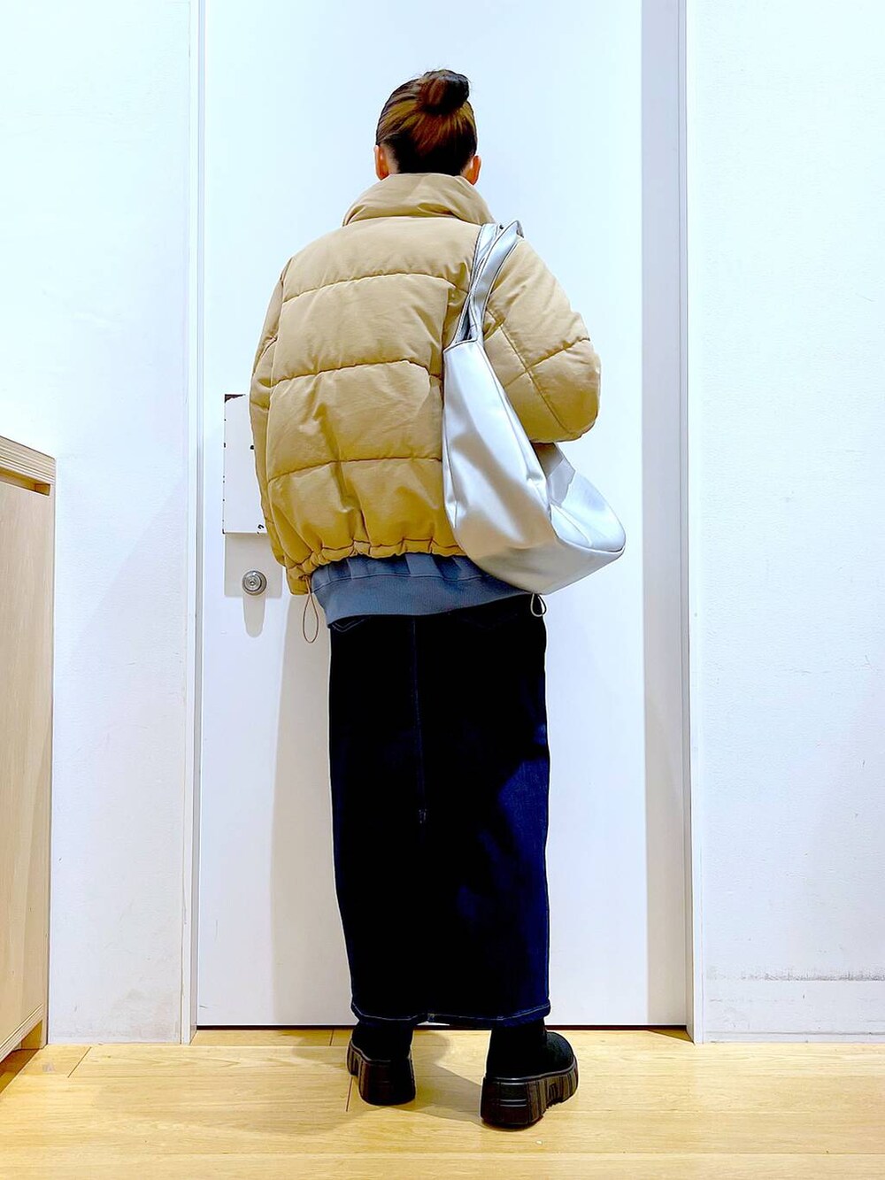 シルバー系のトートバッグ、ベージュ系のナイロンジャケット、ブルー系のデニムスカートを着用したレディースの冬コーディネートの5枚目の写真