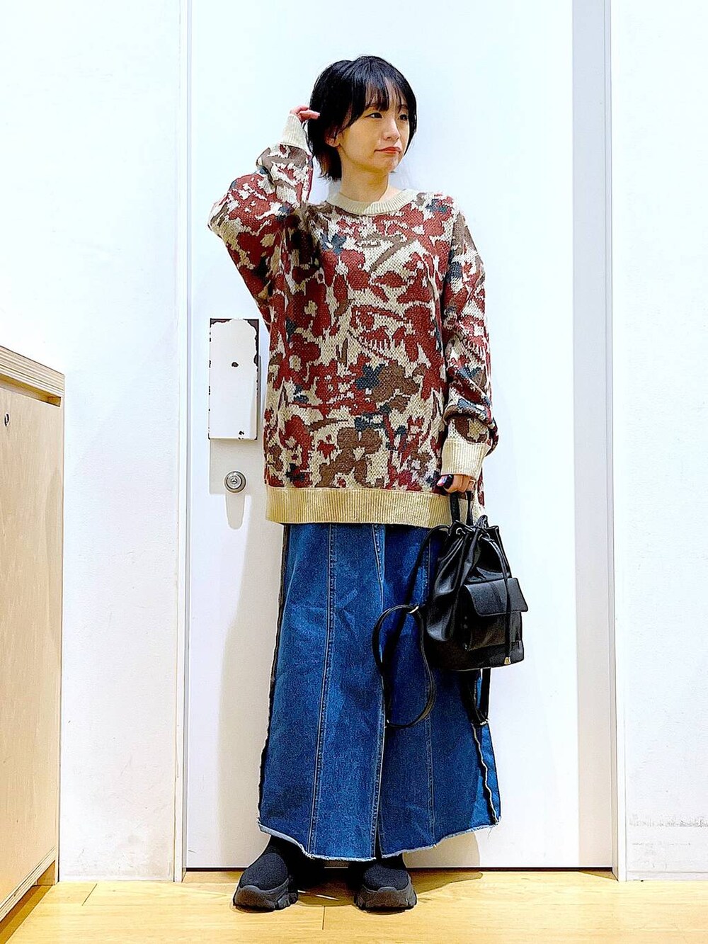 ブラック系のバックパック/リュック、ブルー系のデニムスカート、ブラック系のブーツを着用したレディースの冬コーディネートの2枚目の写真