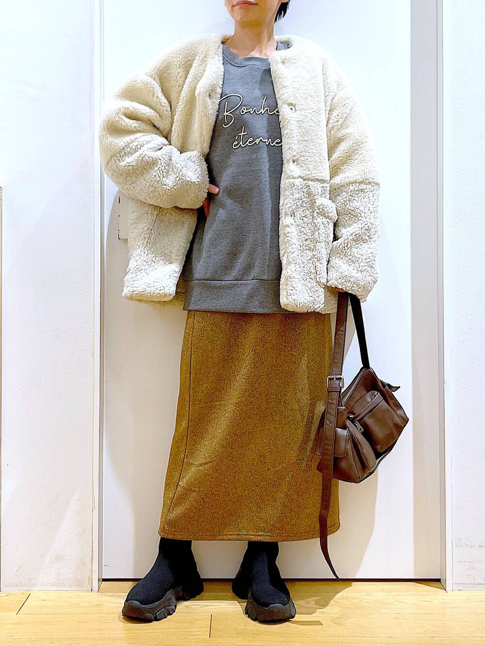 ベージュ系のブルゾン、ブラック系のブーツ、ブラウン系のショルダーバッグを着用したレディースの冬コーディネートの6枚目の写真