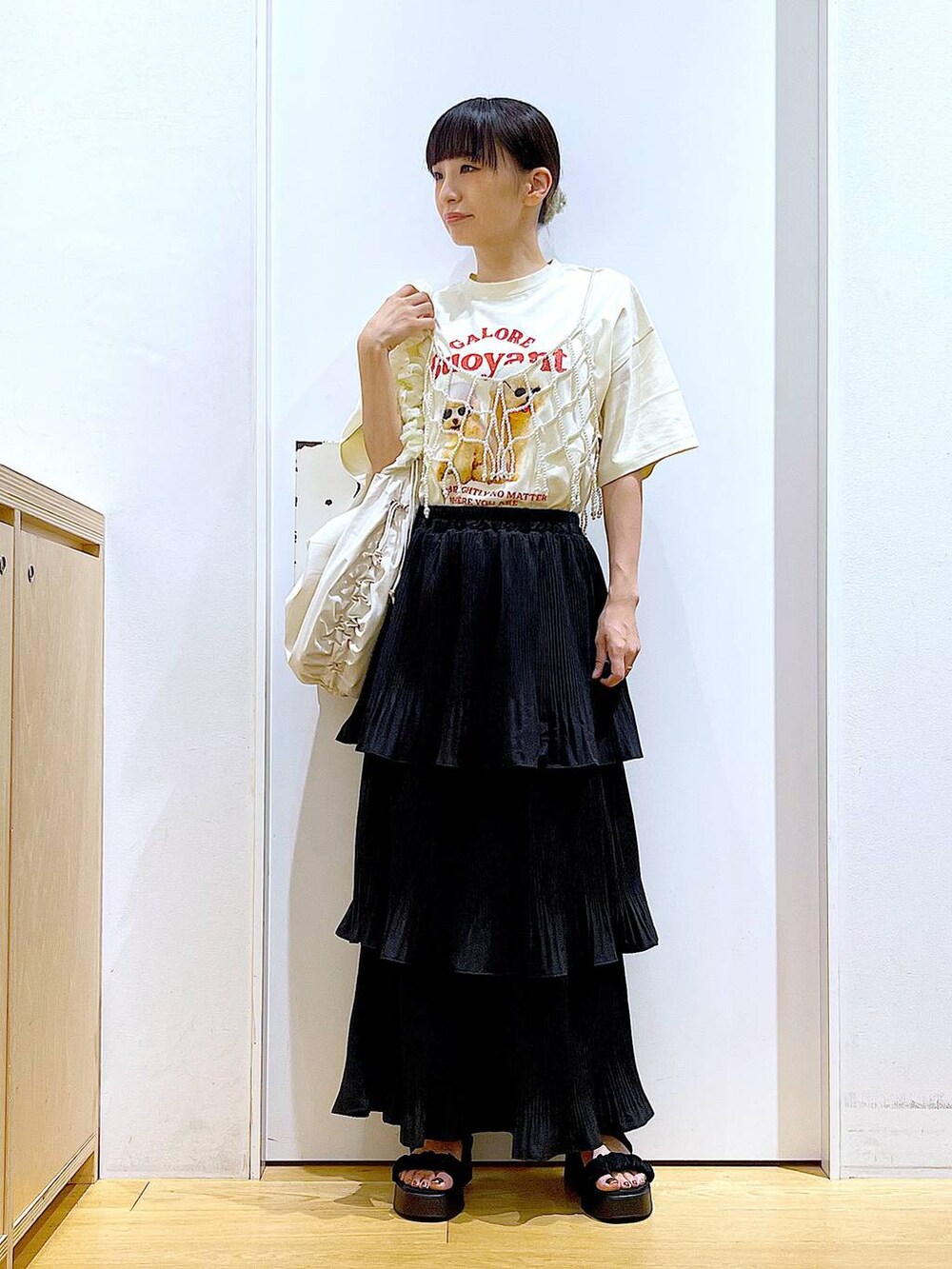 ブラック系のスカート、ブラック系のサンダル、ホワイト系のベストを着用したレディースの秋コーディネートの2枚目の写真